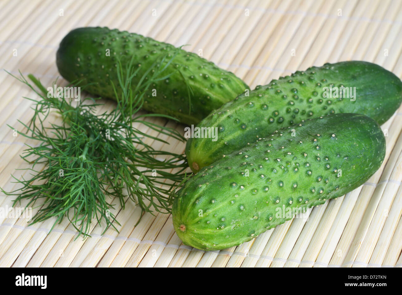 Cetrioli freschi e aneto sul tappetino di bambù, close up Foto Stock