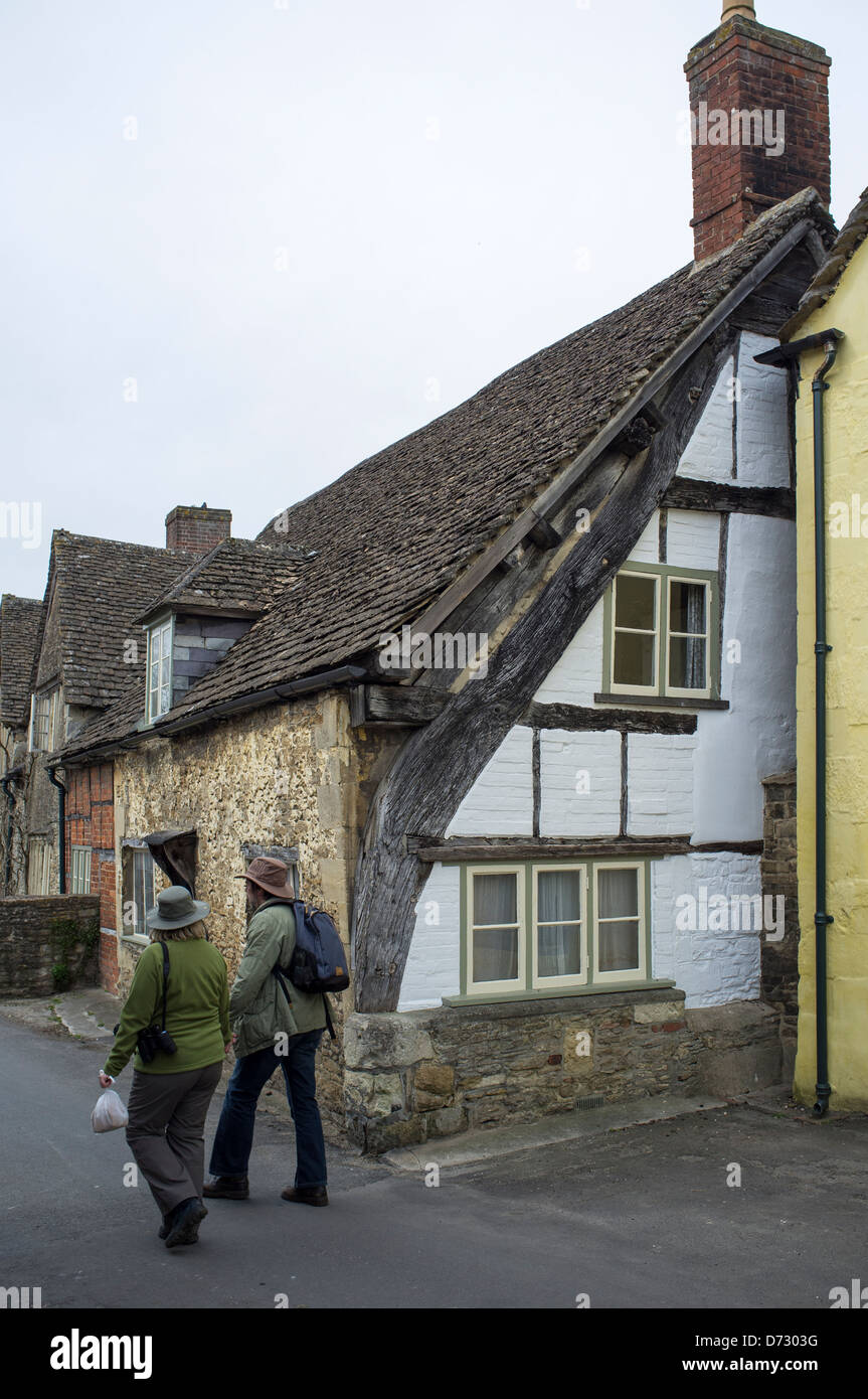 I turisti a piedi passato metà edificio con travi di legno a Lacock Village Foto Stock