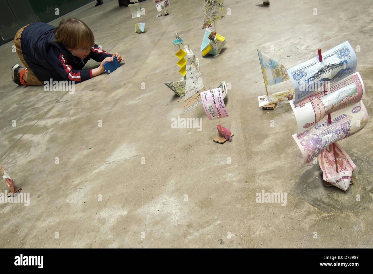 Susan Stockwell's Sail Away progetto presso la Tate Modern come parte della serie il collegamento ipertestuale il 27 e 28 aprile. Sail Away è una grande installazione di scala con centinaia di piccole imbarcazioni realizzate dalla carta moneta, biglietti, aghi da maglia e mappe. Basato sulle idee di connessioni tramite agenzia di viaggio, scambi commerciali e rotte, mappatura e coloniali/storie personali, salpate invita i bambini a interagire con il lavoro aggiungendo le proprie imbarcazioni per la flottiglia. La Tate Modern di Londra, UK, 27 aprile 2013. Foto Stock