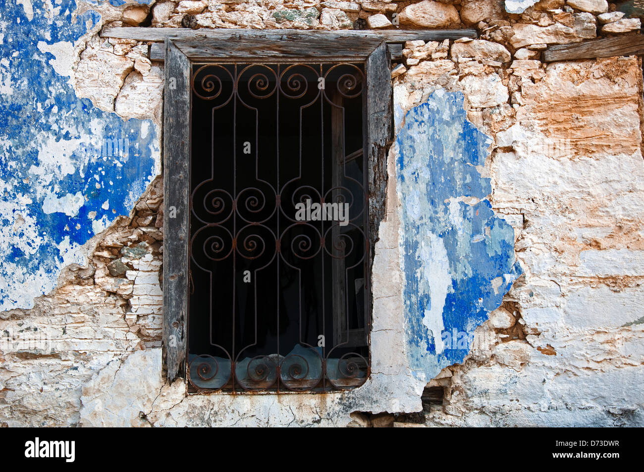 Vecchia finestra con griglia di ferro in weathered facciata della casa con peeling vernice (Grecia) Foto Stock