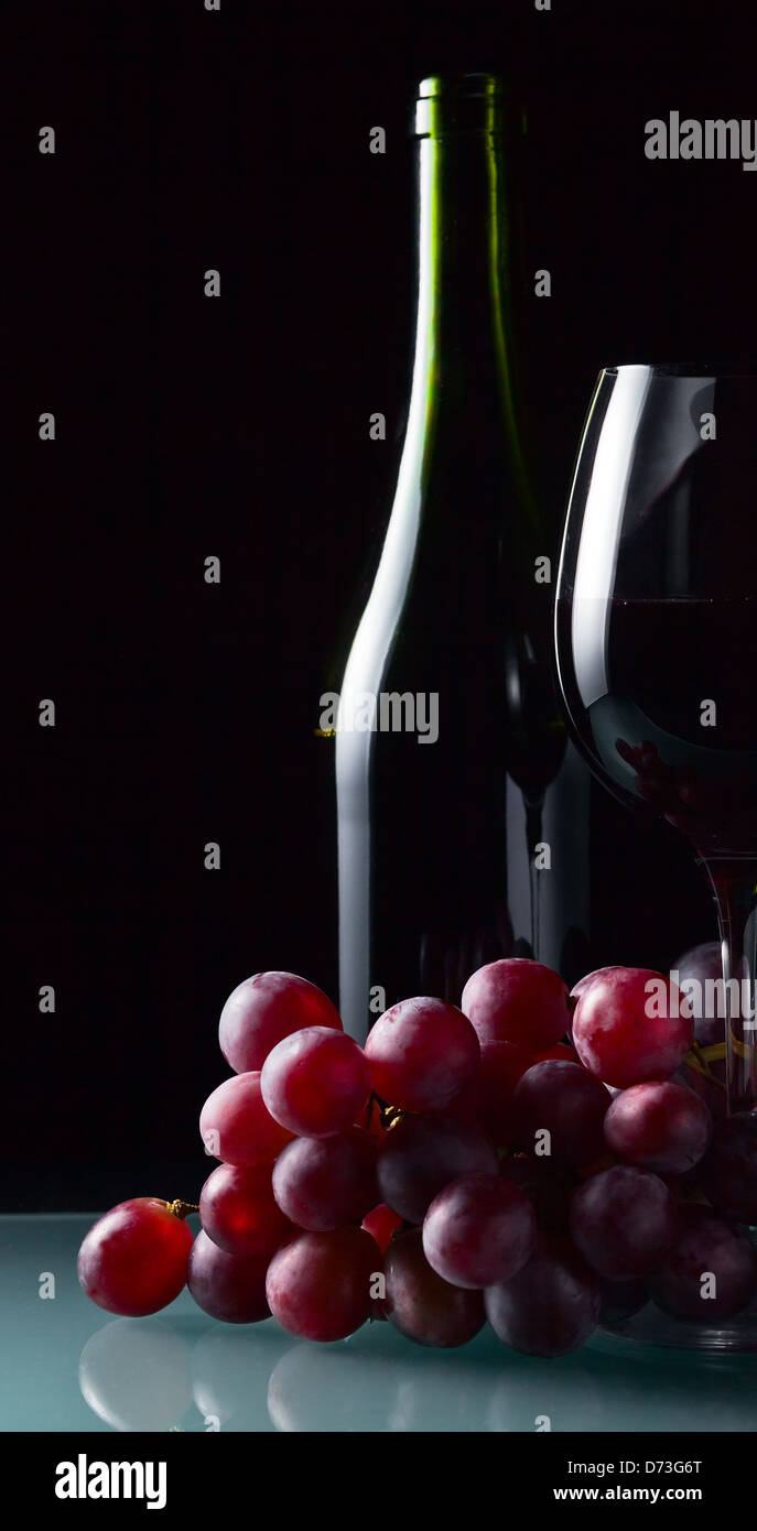 Uva e vetro con vino rosso su sfondo nero Foto Stock