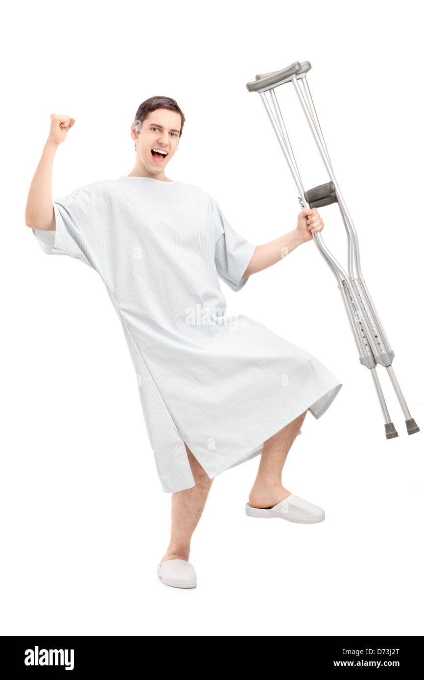 A piena lunghezza Ritratto di un felice paziente di sesso maschile in abito ospedale azienda stampelle e gesticolando felicità Foto Stock