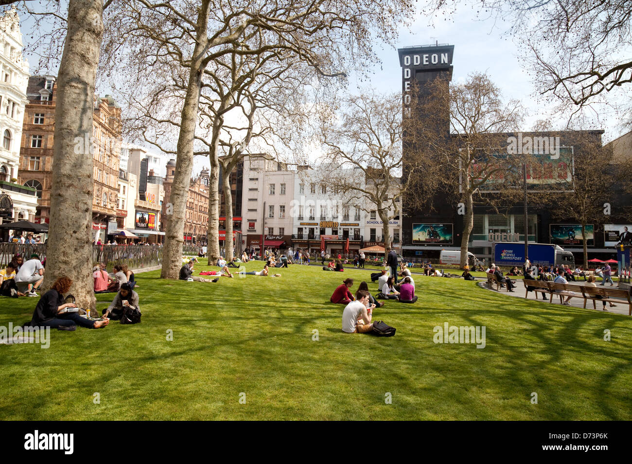 La Gente seduta sul prato in una giornata di sole, Leicester Square Londra WC2, Regno Unito Foto Stock
