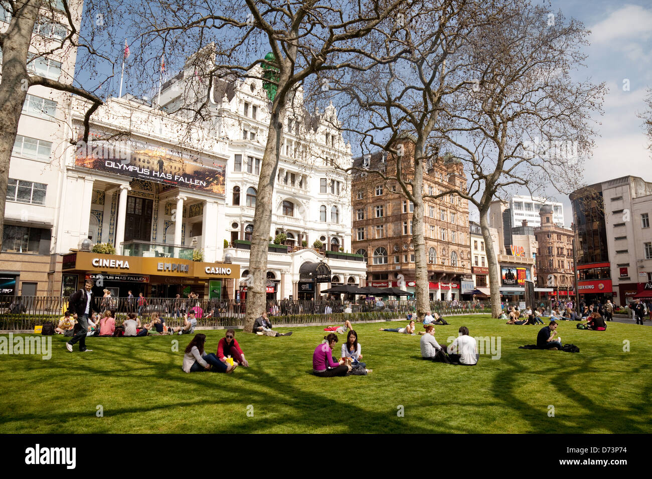La gente seduta godendo il sole in primavera, Leicester Square, Central London WC2, Regno Unito Foto Stock