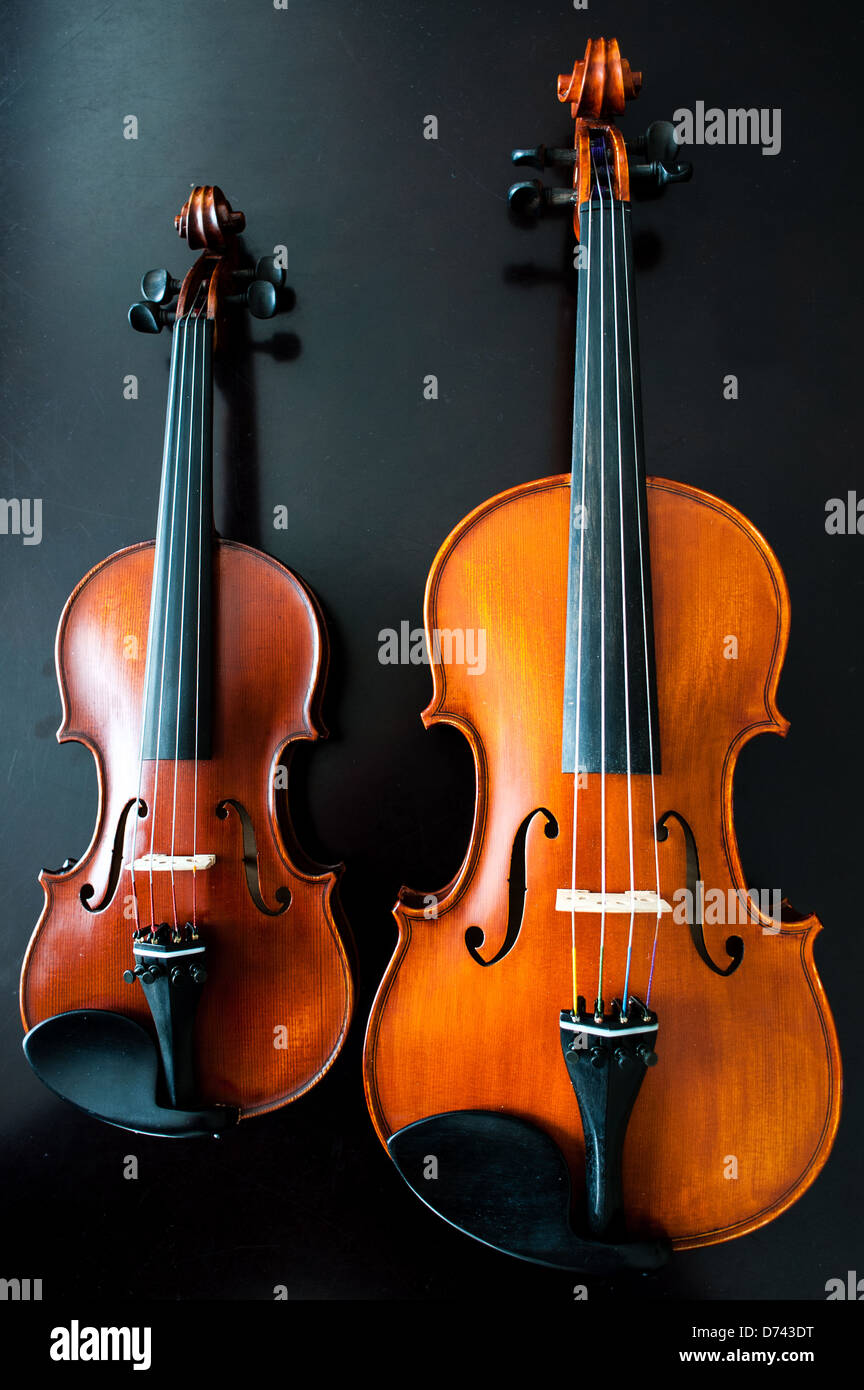 Una full size (4/4) e quarto dimensioni (1/4) violino a fianco a fianco in un studio shot. Foto Stock