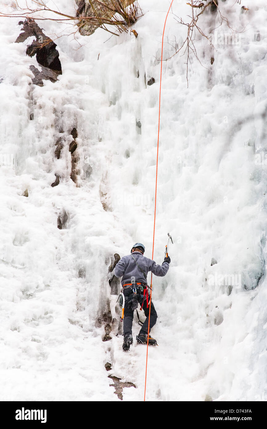 Un alpinista fermi se stesso sulla sosta presso l'approccio di una cascata. Foto Stock