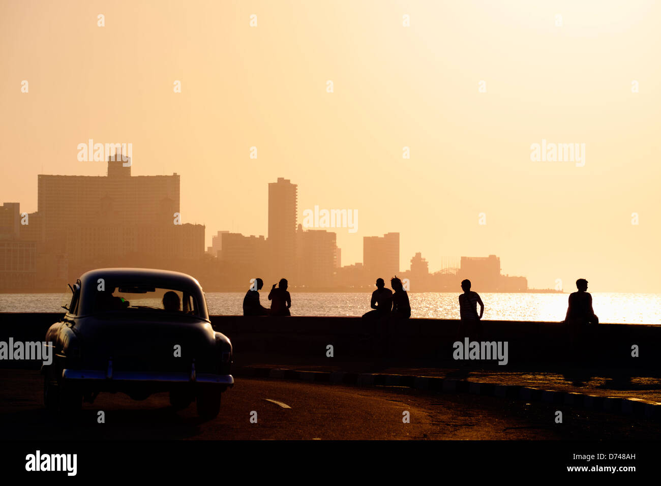 Skyline di La Habana, Cuba, al tramonto, con auto d'epoca sulla strada e la gente seduta sul Malecon. Spazio di copia Foto Stock