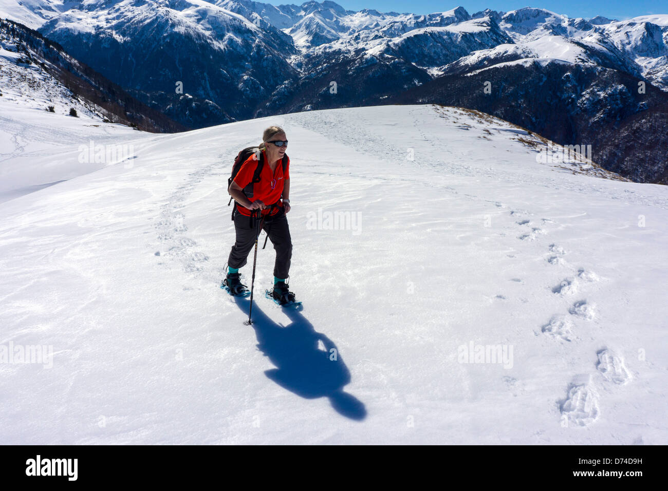 Figura femminile in rosso con le racchette da neve, Plateau de Beille, Ariège, Pirenei francesi Foto Stock