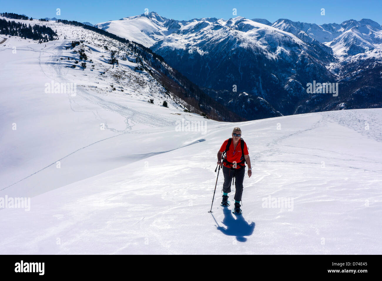 Figura femminile in rosso con le racchette da neve, Plateau de Beille, Ariège, Pirenei francesi Foto Stock