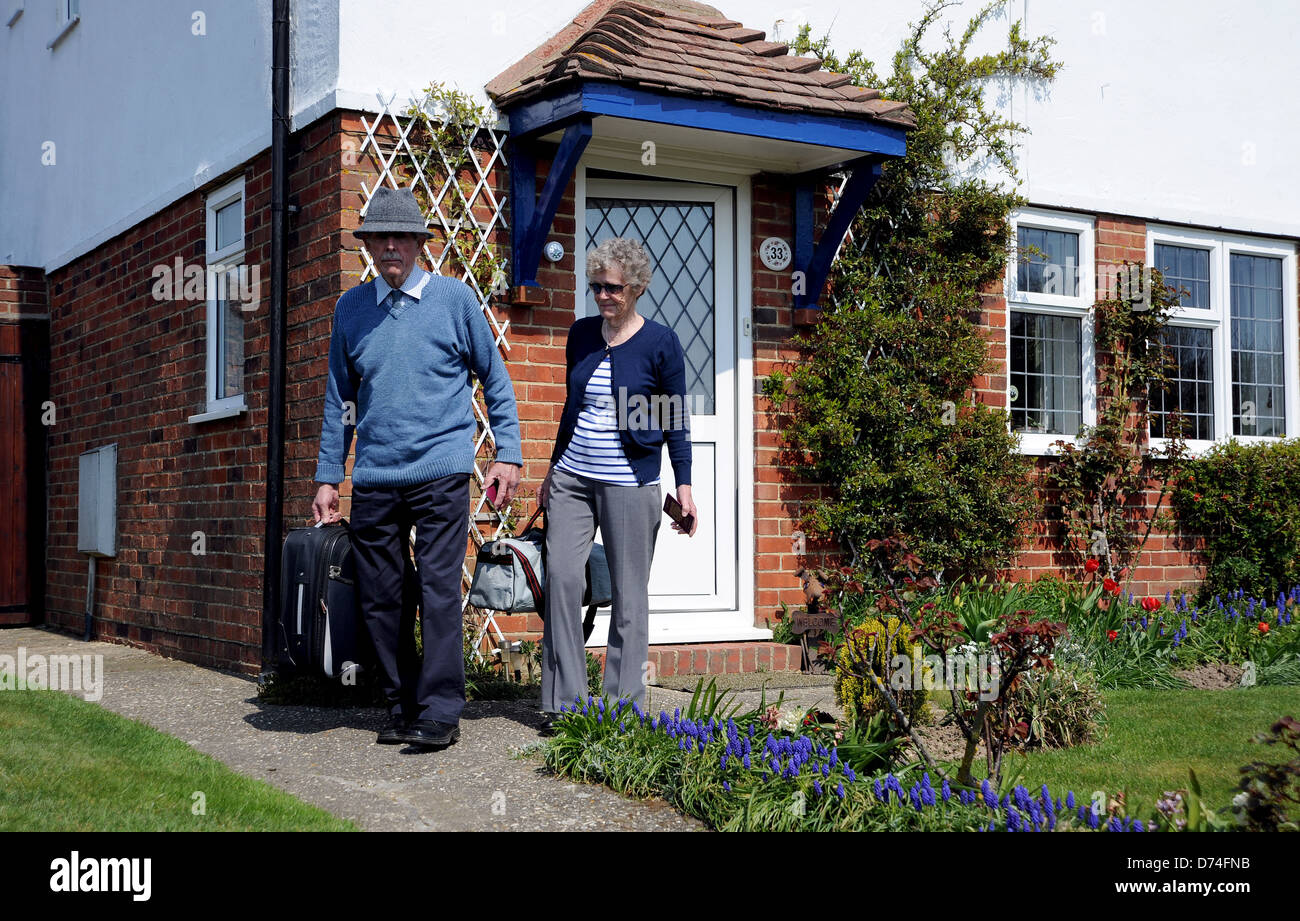 Coppia di anziani con sacchetti confezionati e dei passaporti pronti per un viaggio all'estero a lasciare la loro casa Foto Stock