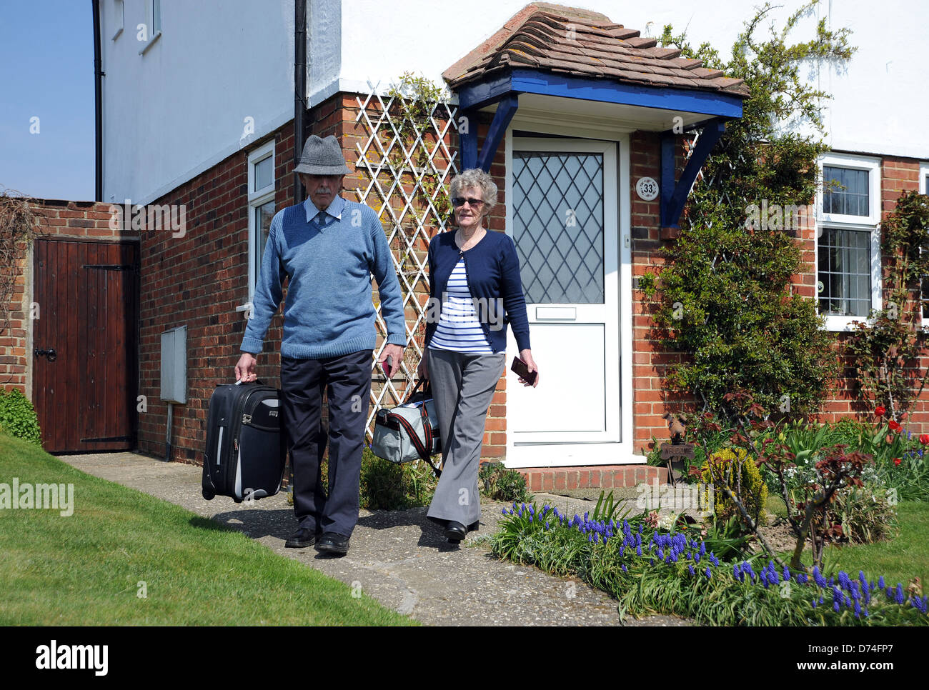 Coppia di anziani con sacchetti confezionati e dei passaporti pronti per un viaggio all'estero a lasciare la loro casa Foto Stock
