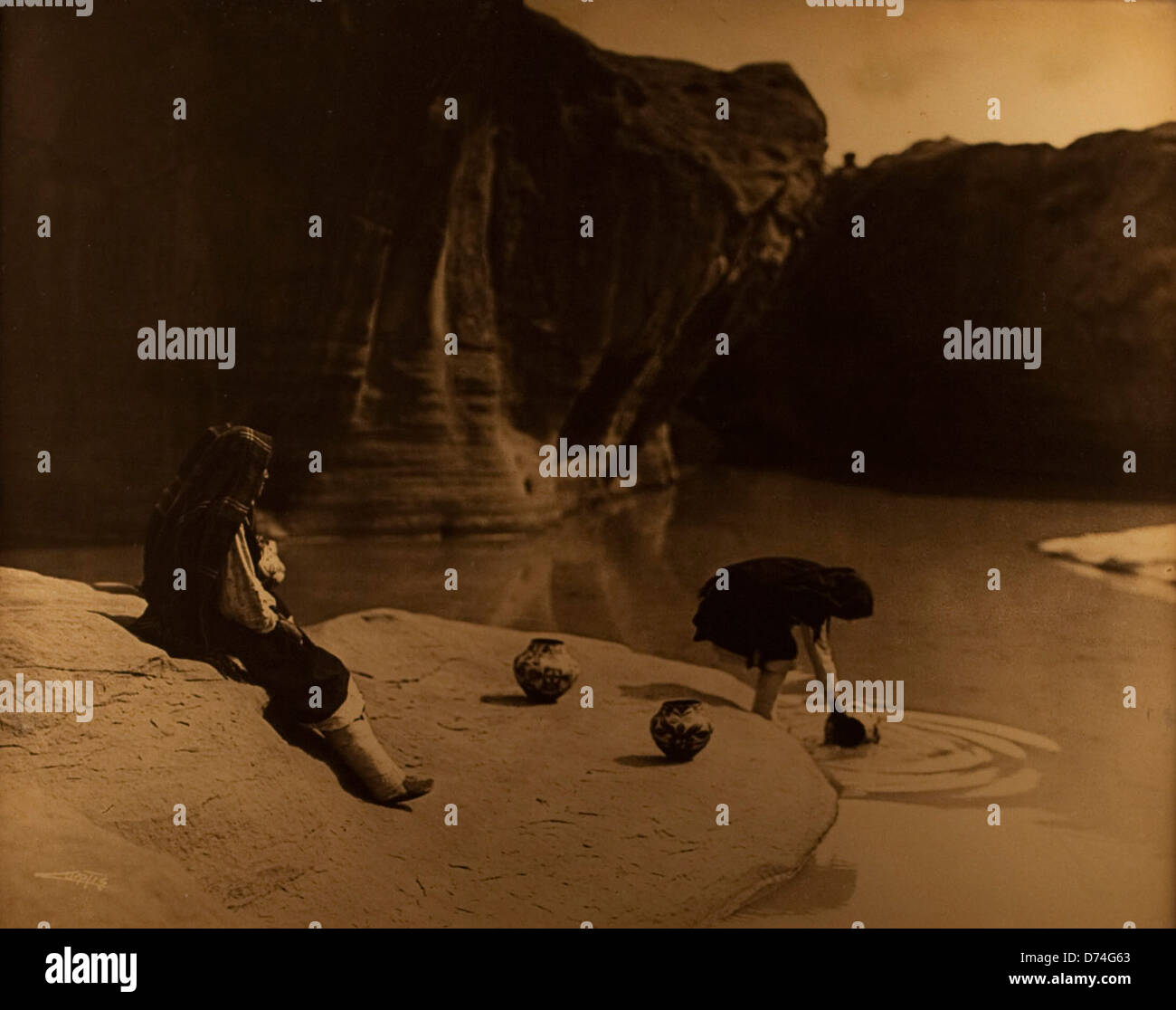 Questa fotografia di Edward Sheriff Curtis mostra i nativi americani all'Old Well di Acoma, catturando un momento di significato culturale. Curtis è rinomato per i suoi ritratti della vita dei nativi americani, che offrono uno sguardo alle tradizioni indigene. Foto Stock