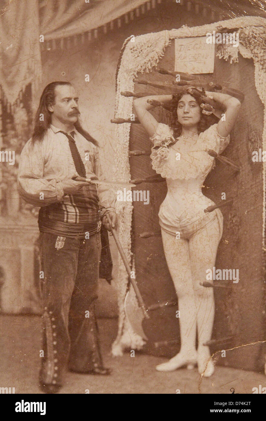 Questa fotografia senza titolo raffigura il signor Arcaris, un lanciatore di coltelli, e sua sorella Miss Rose Arcaris, probabilmente parte di un circo o di una performance. L'immagine cattura un momento dal loro atto. Foto Stock