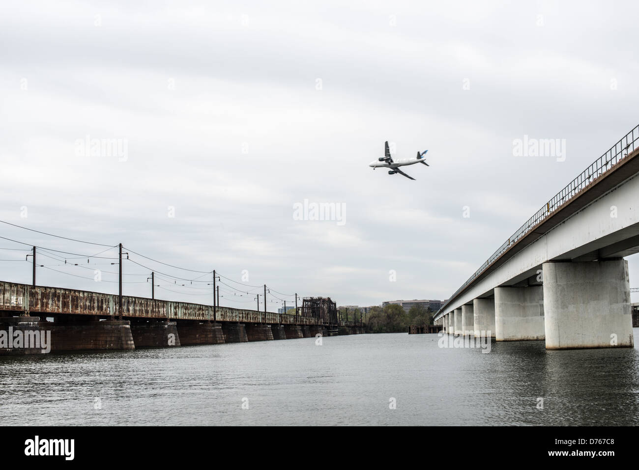 14th Street Bridge Airplane Landing Washington DC Virginia // due dei cinque ponti che compongono quello che è comunemente noto come 14th Street Bridge che attraversa il Potomac e collega Washington DC con la Virginia. Sulla destra c'è il Charles R. Fenwick Bridge, che trasporta i treni pendolari della Washington Metro. A sinistra c'è il ponte lungo, che trasporta il traffico ferroviario. Al centro c'è un aereo che arriva per atterrare all'aeroporto nazionale Reagan di Alexandria, Virginia. Foto Stock