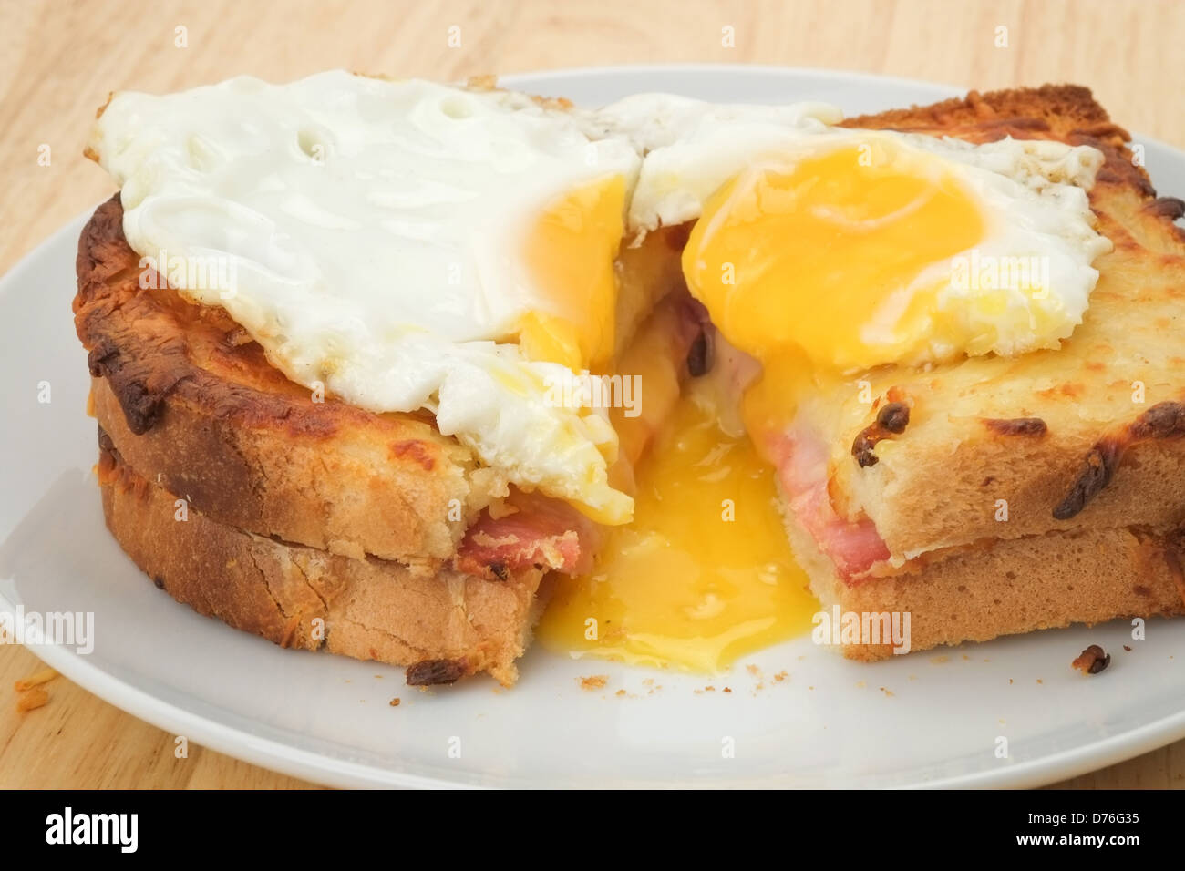 Un tostati e tagliata aperta Croque Madame sandwich con formaggio fuso e prosciutto e rabboccato con un uovo fritto. Foto Stock