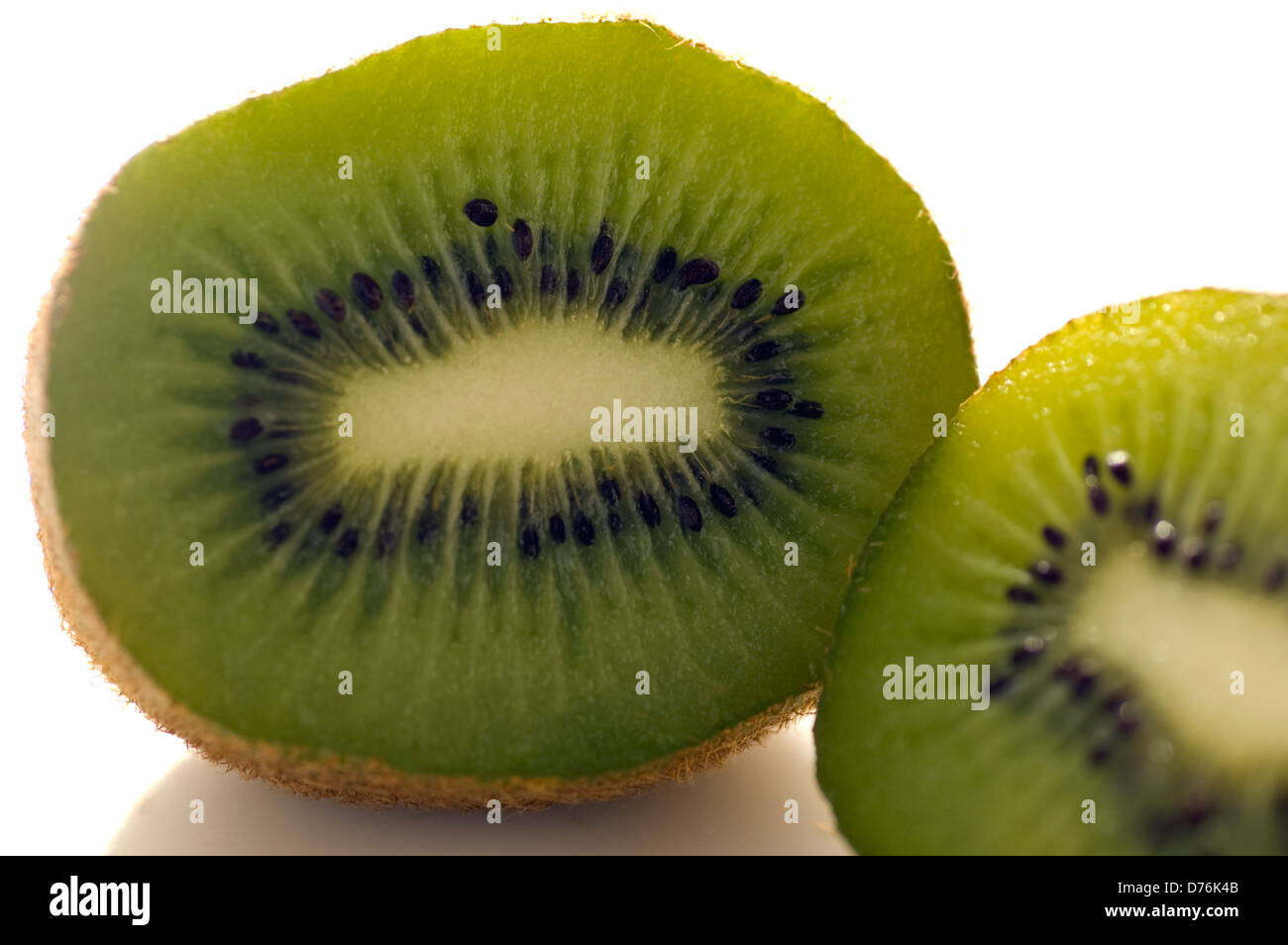 Organici di Kiwi tagliato in due metà e fotografati in perspex bianco usando la luce naturale per uso magazzino. Foto Stock