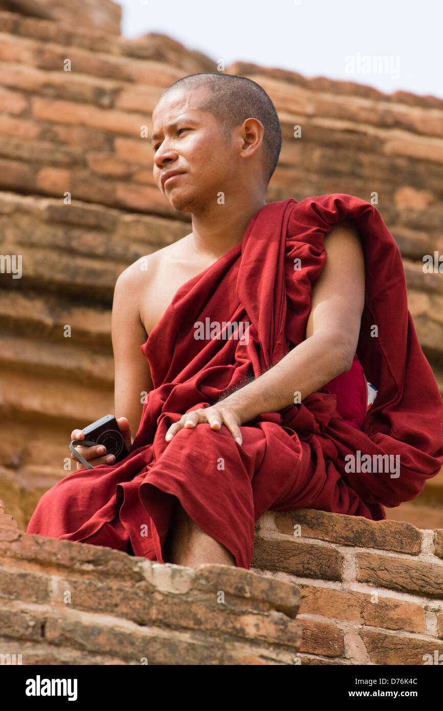 Giovane Monaco con una telecamera, seduti su uno stupa di Bagan, Myanmar Foto Stock