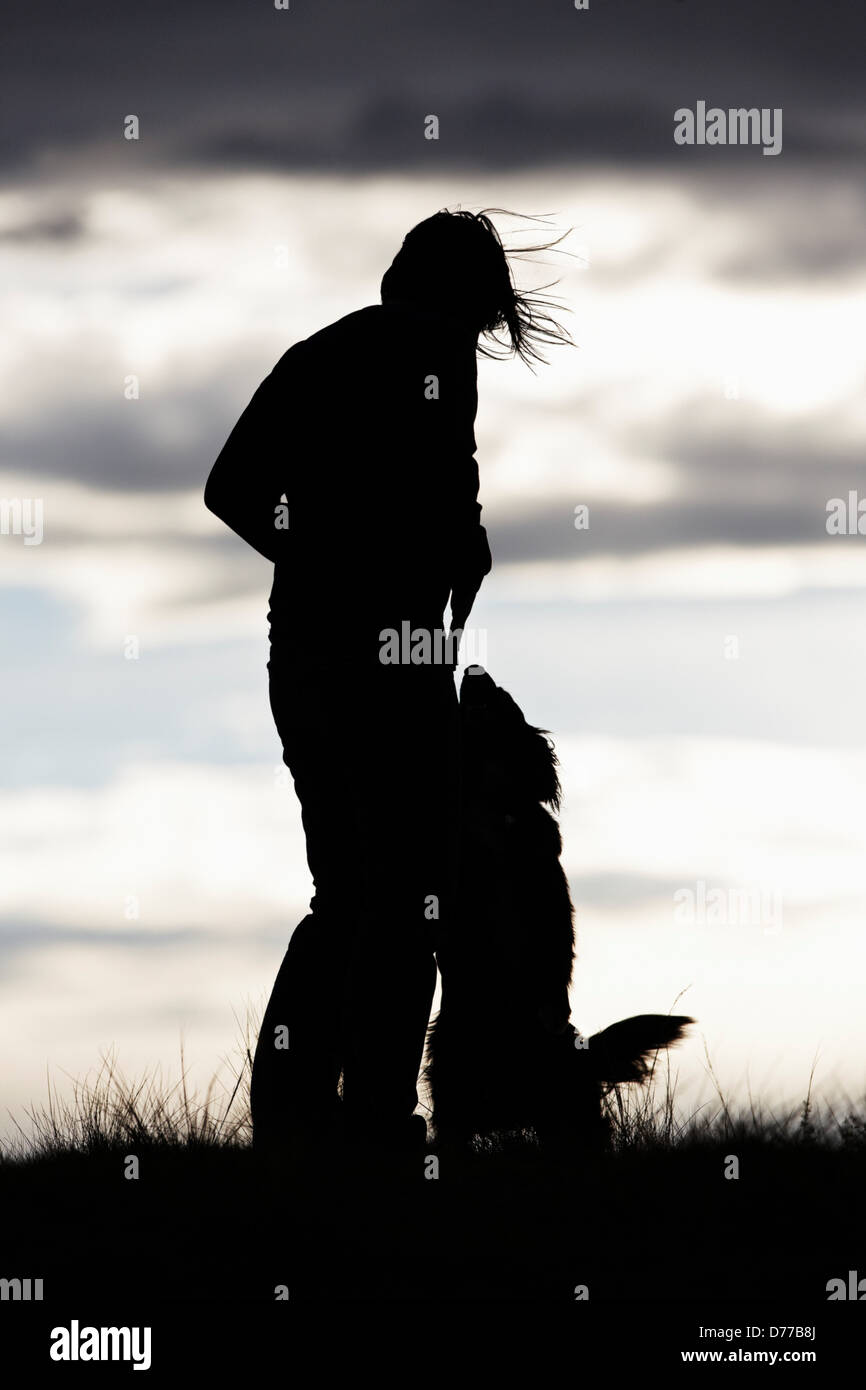 Silhouette donna cane al tramonto Foto Stock
