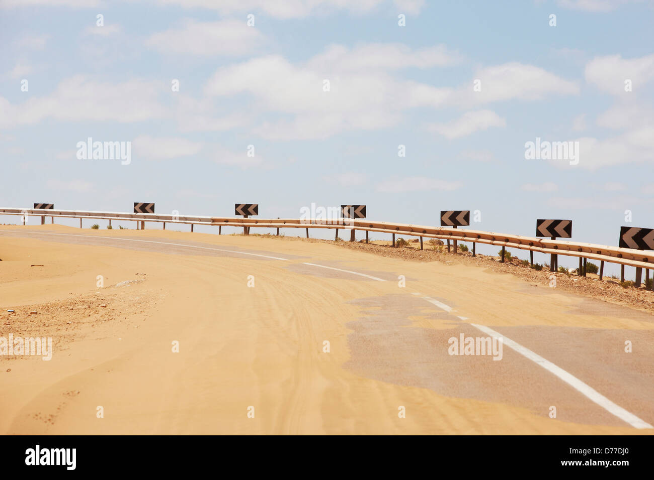 Strada coperta da sabbia recente tempesta di sabbia di Costa Atlantica Marocco dove Sahara Desert incontra il mare del sud del Marocco Foto Stock
