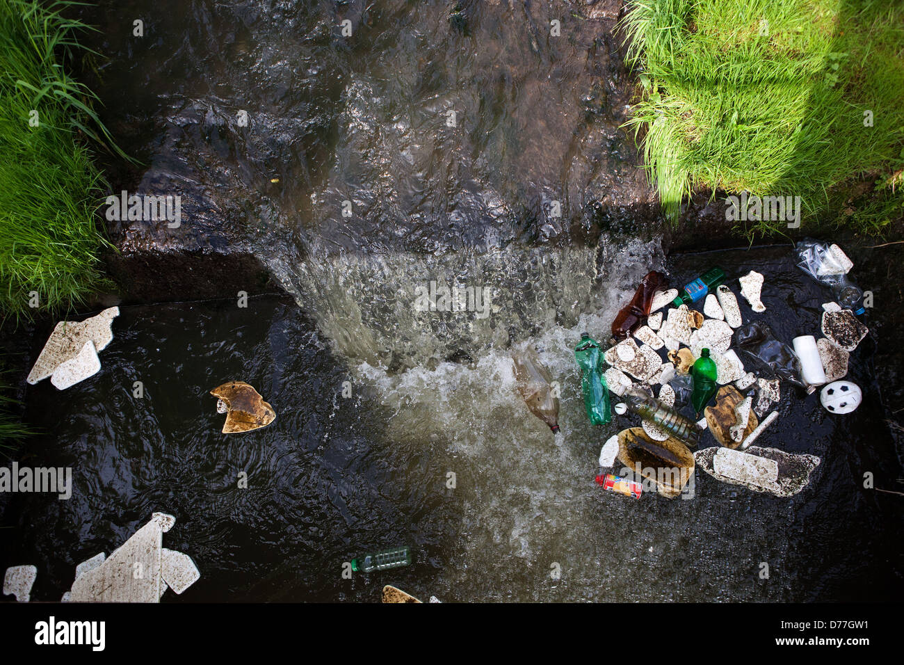 Rifiuti di plastica galleggianti in un piccolo fiume, inquinamento Foto Stock