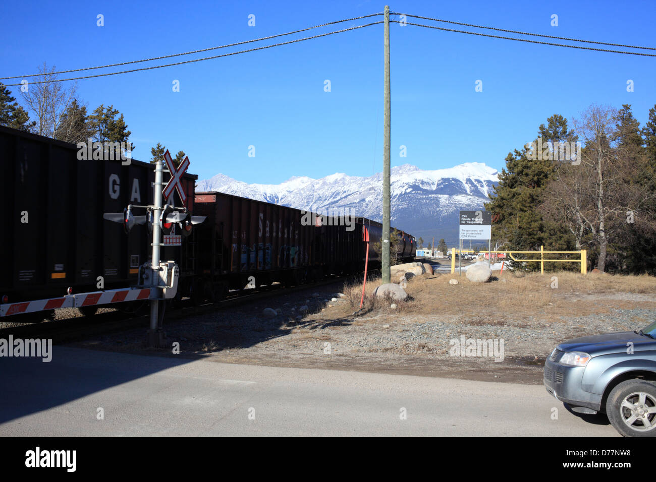 Treno passare e una vettura in attesa di continuare nel villaggio di Jasper (Alberta) Foto Stock