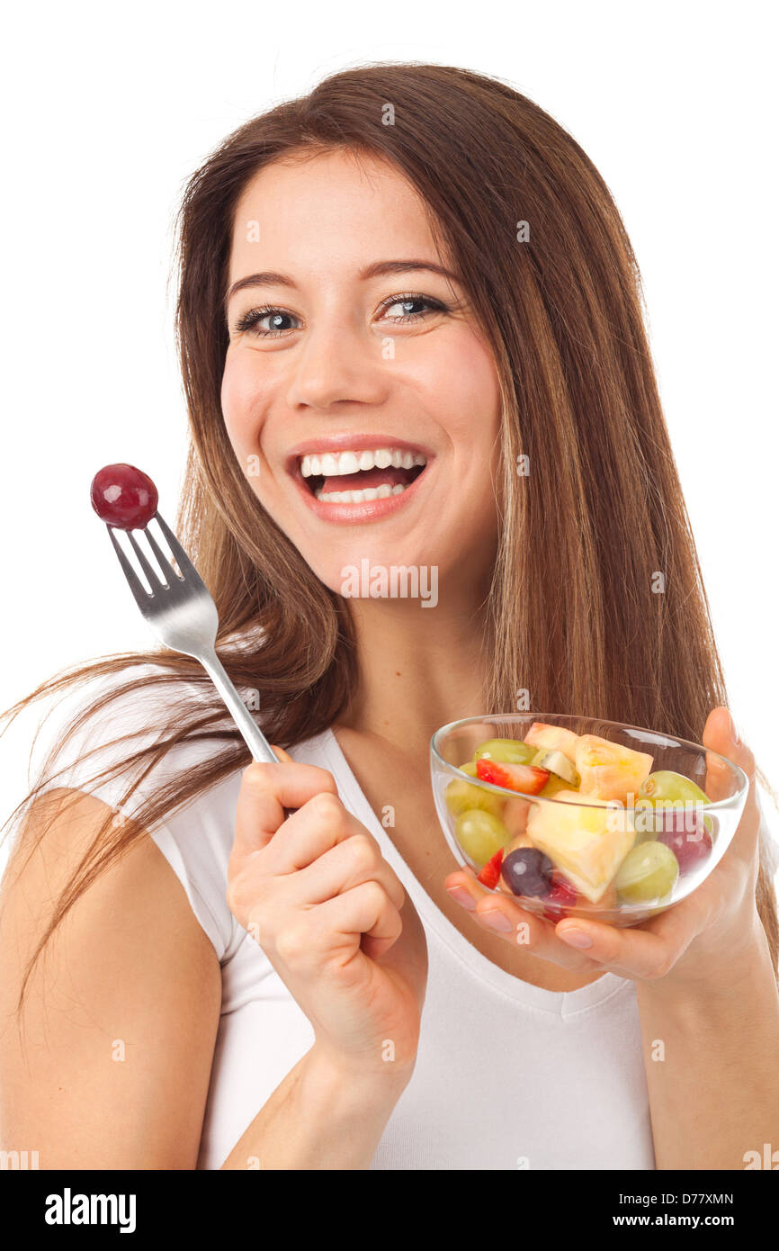Bella donna mangiare frutta e sorridente, isolato su bianco Foto Stock
