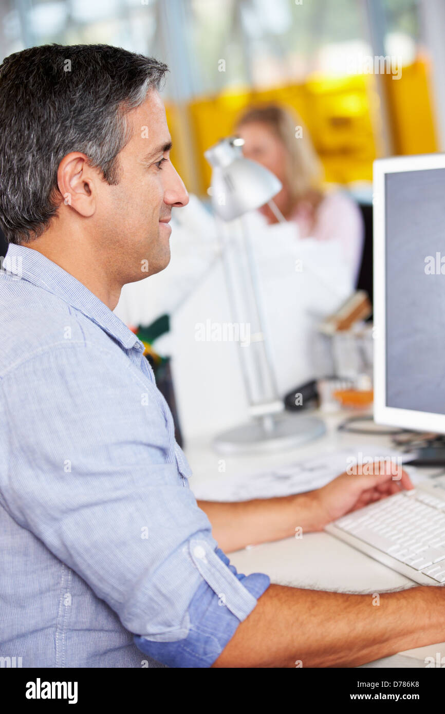 Uomo che lavora alla reception In occupato Ufficio creativo Foto Stock