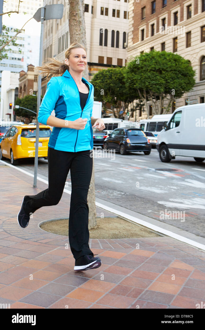 Donna in corsa lungo la strada urbana Foto Stock