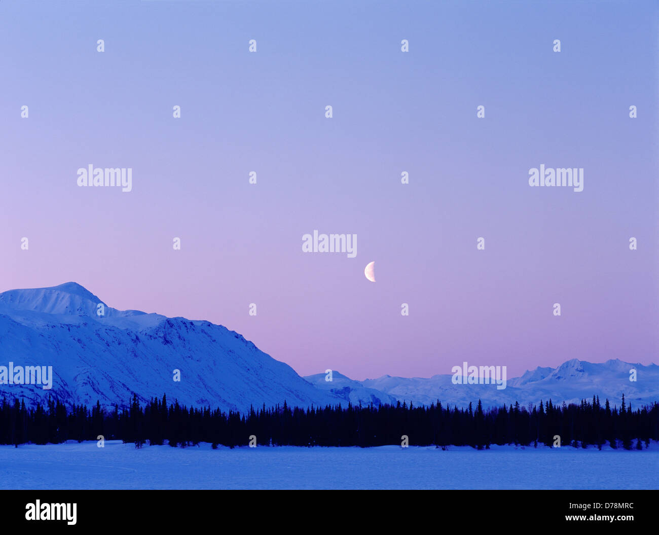 Quarto di luna il dito sopra il lago di Tordillo montagne all'alba d'inverno Alaska. Foto Stock