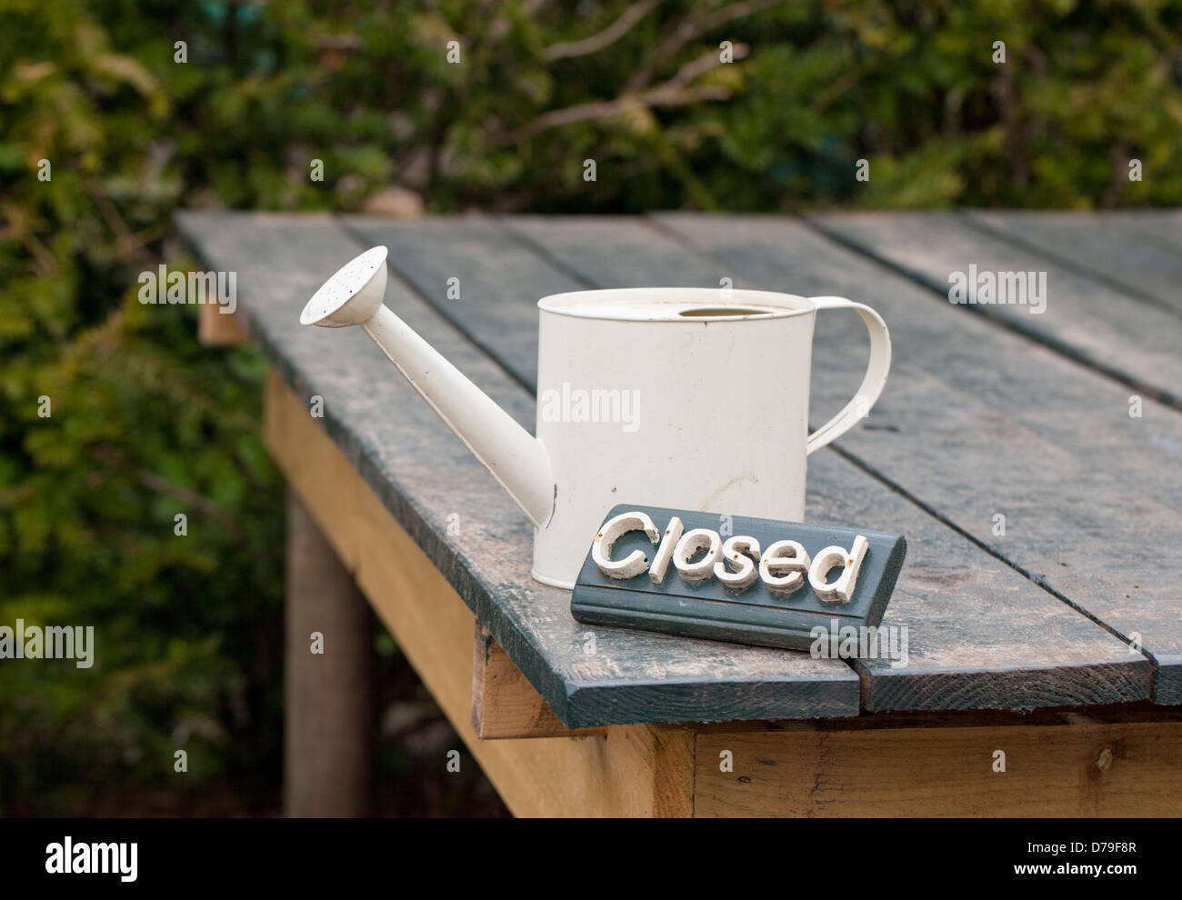 Panca da giardino con cartello chiuso e lattina di irrigazione panna piccola, UK Foto Stock