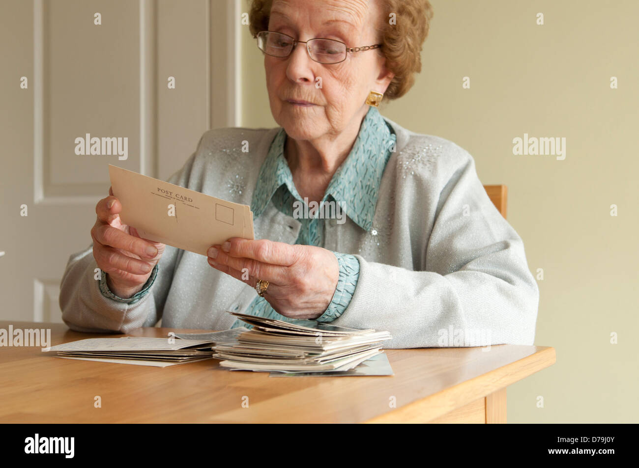 Donna anziana guarda vecchie cartoline Foto Stock