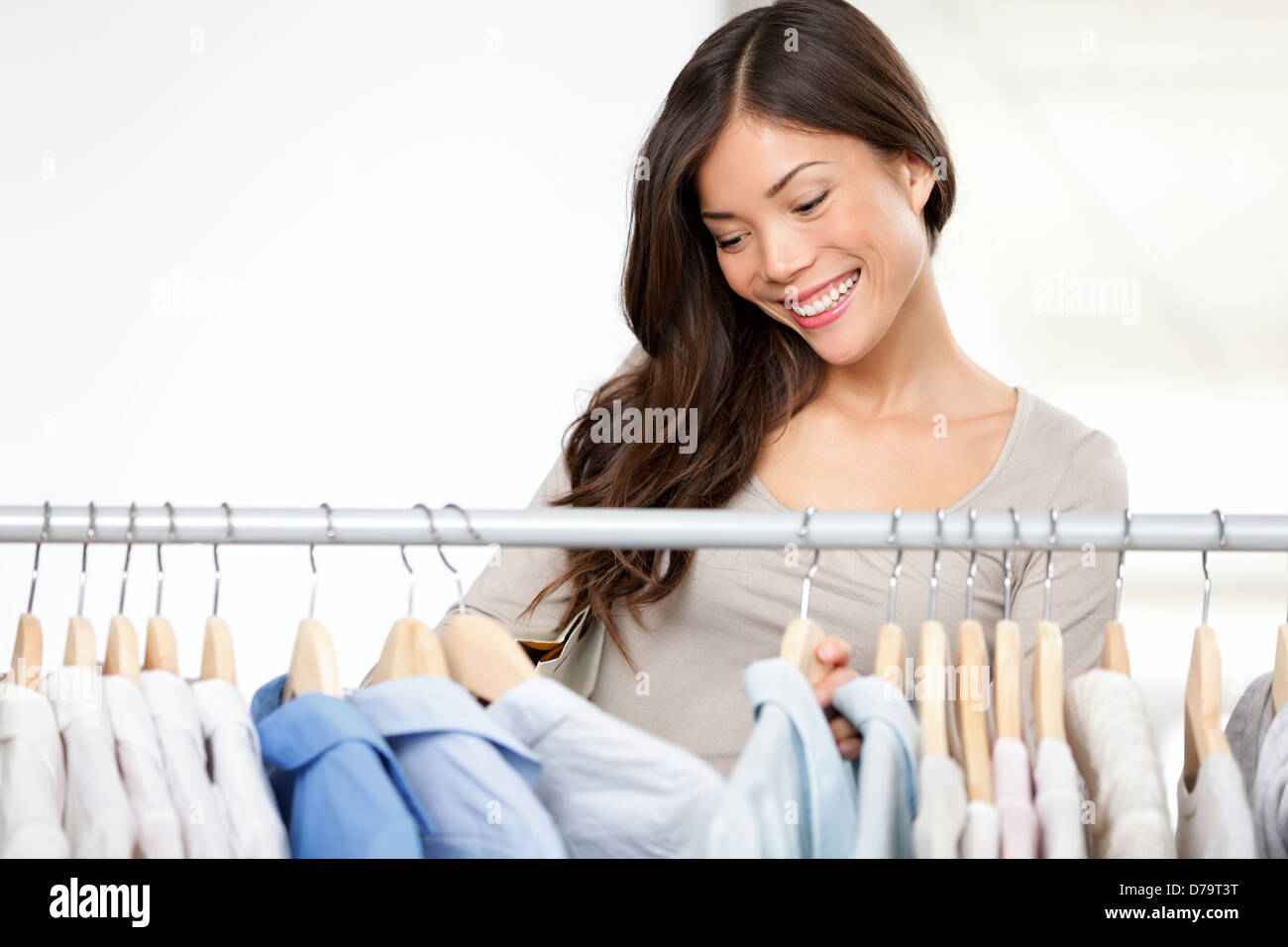 Donna abiti da shopping nel negozio di abbigliamento guardando camicie abbigliamento sul rack. Bella mista multiculturale di razza caucasica femmina asiatica sorridente modello h Foto Stock