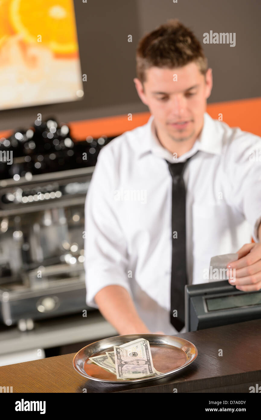 Giovane barista in uniforme tenendo contanti di USD nel bar Foto Stock