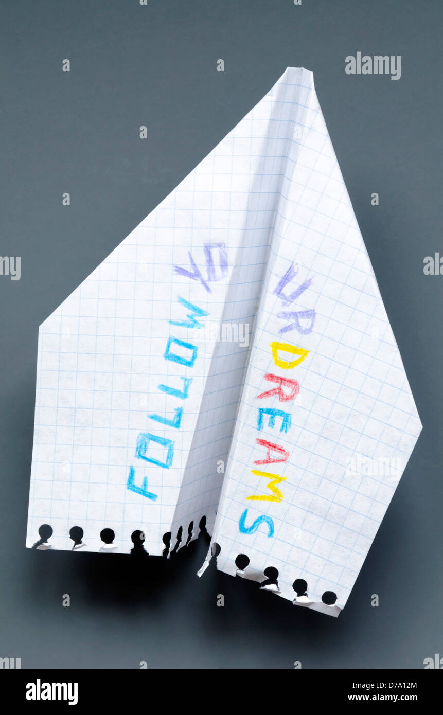 Aeroplano di carta con seguire i vostri sogni una frase su sfondo grigio scuro Foto Stock