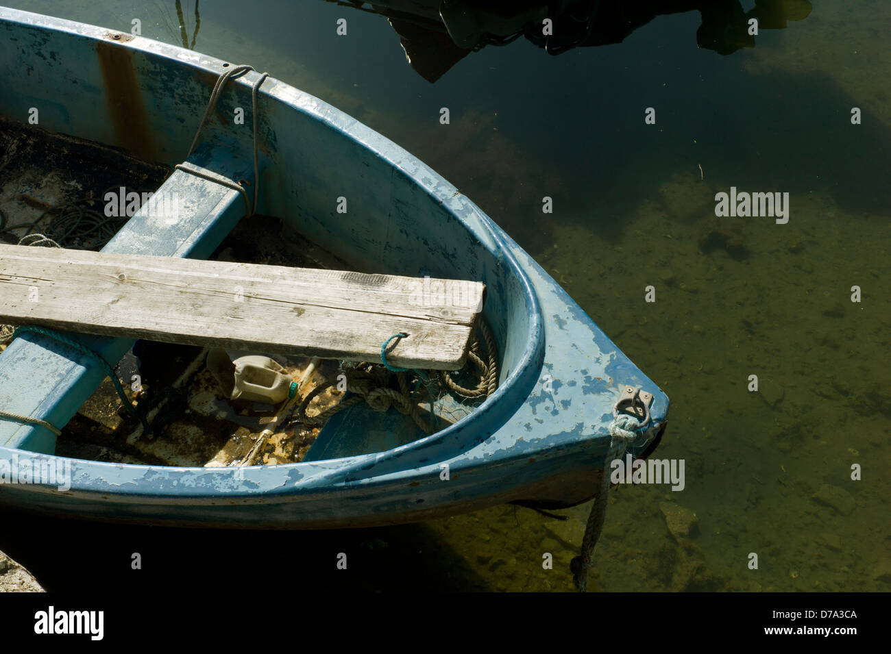 Vecchio dinghy piena di spazzatura ormeggiata in acqua poco profonda Foto Stock