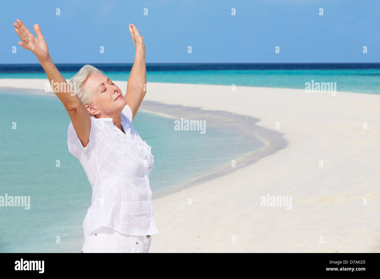 Senior donna con le braccia aperte sulla bella spiaggia Foto Stock