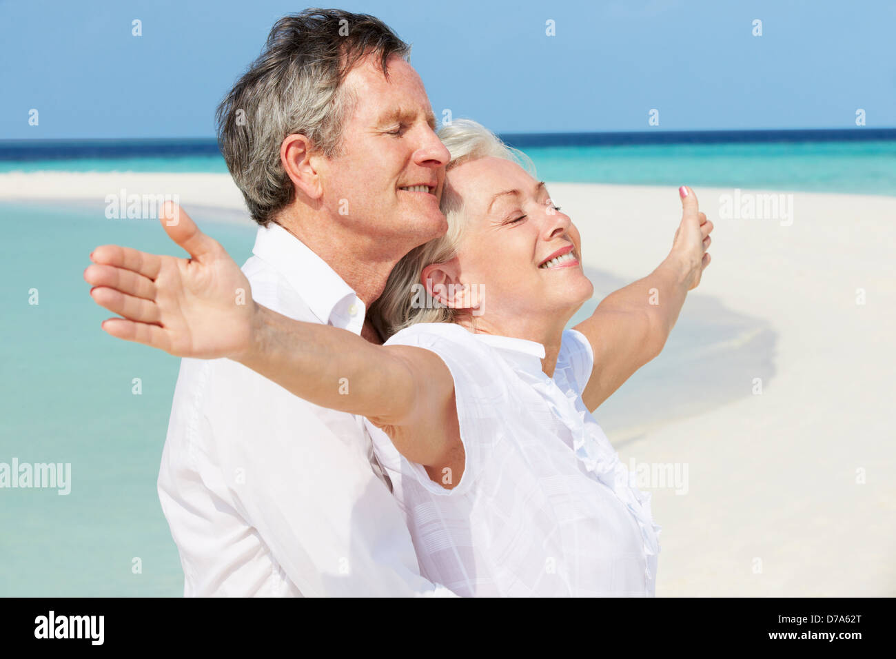 Coppia senior Withs braccia allargate sulla bellissima spiaggia Foto Stock