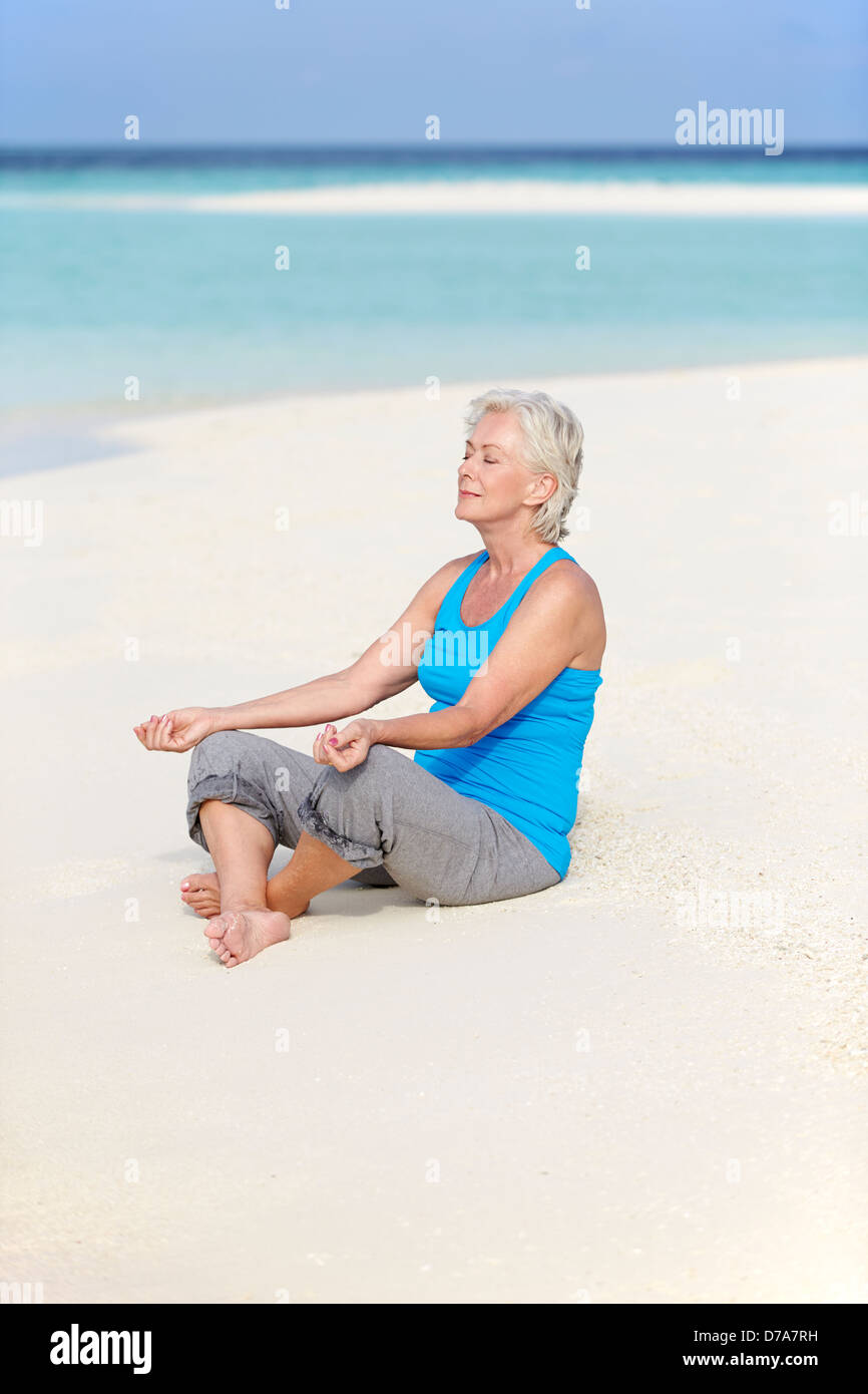 Senior donna meditando sulla bellissima spiaggia Foto Stock
