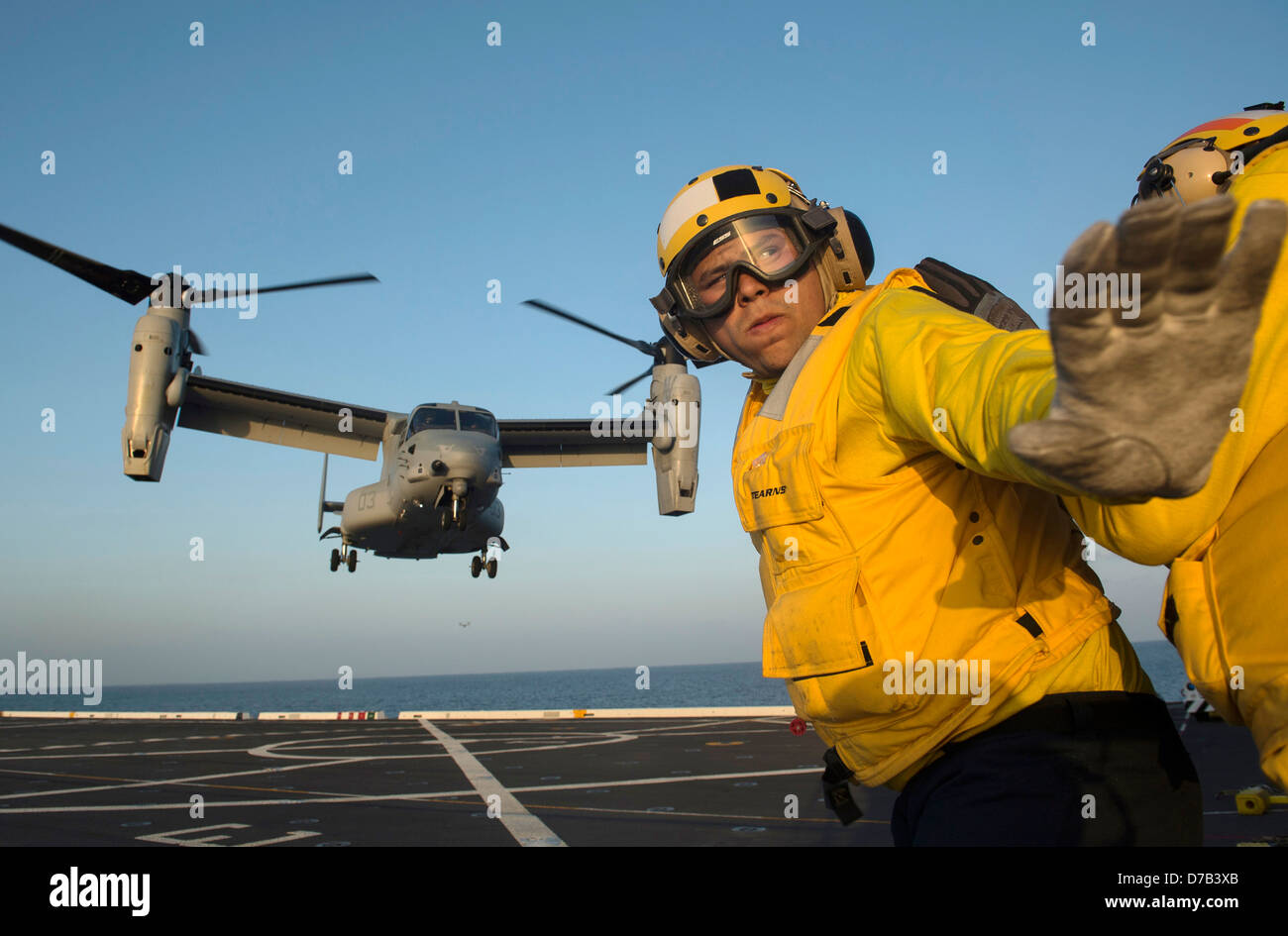 Un Navy US aviazione di Boatswain Mate dirige il lancio di un MV-22 Osprey aeromobile a rotore inclinabile sul ponte di volo del trasporto anfibio Dock nave USS Anchorage Aprile 24, 2013 nell'Oceano Pacifico. Foto Stock