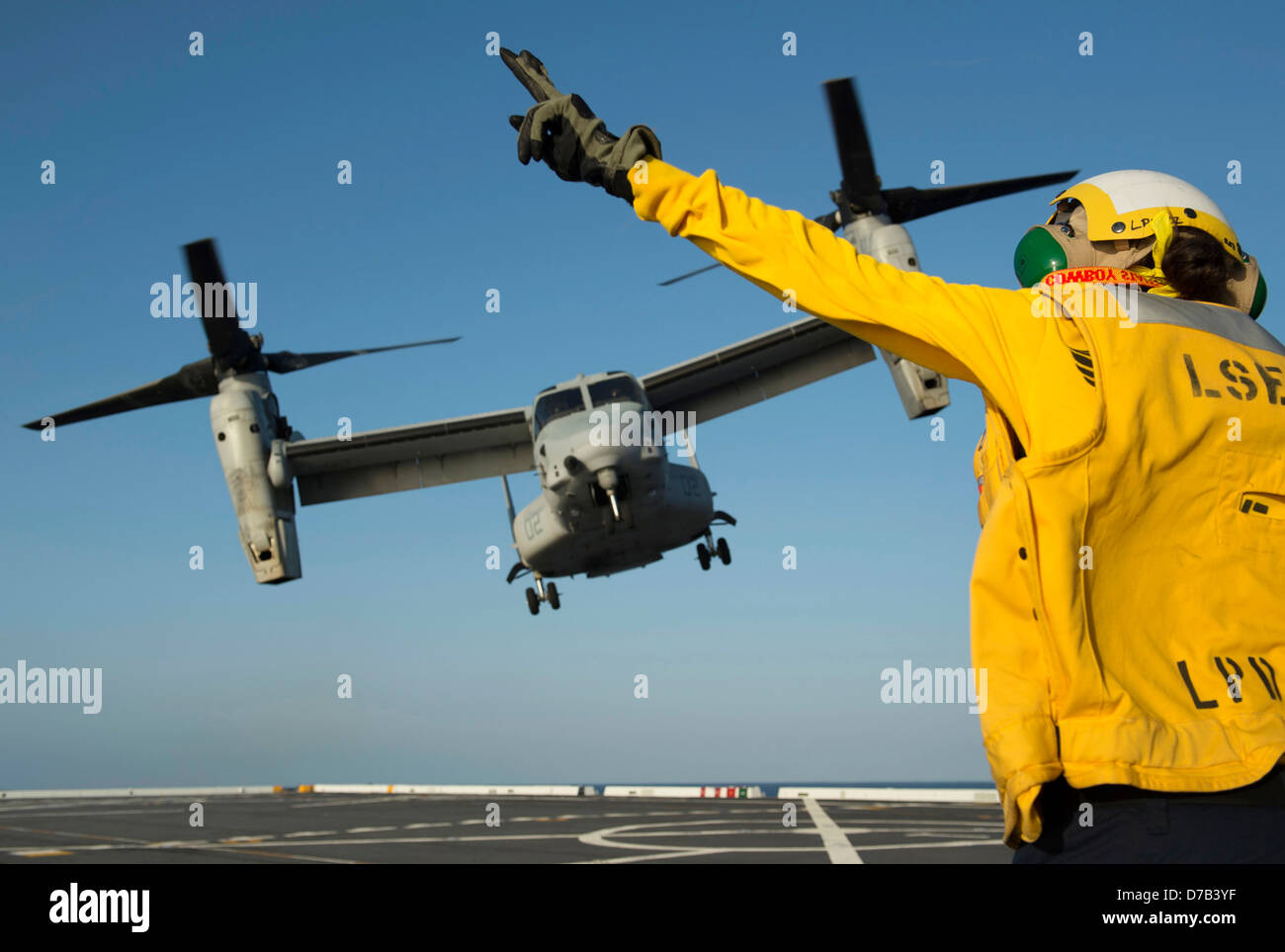 Un Navy US aviazione di Boatswain Mate dirige il lancio di un MV-22 Osprey aeromobile a rotore inclinabile sul ponte di volo del trasporto anfibio Dock nave USS Anchorage Aprile 24, 2013 nell'Oceano Pacifico. Foto Stock
