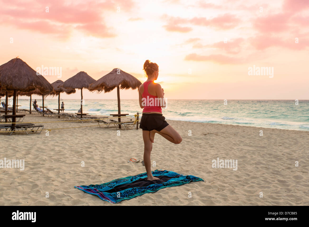 Messico, Playa del Carmen, giovane donna a praticare yoga sulla spiaggia al sorgere del sole Foto Stock