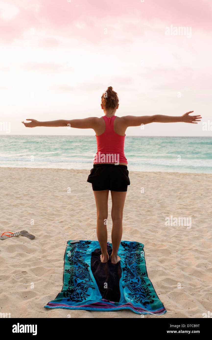 Messico, Playa del Carmen, giovane donna a praticare yoga sulla spiaggia al sorgere del sole Foto Stock