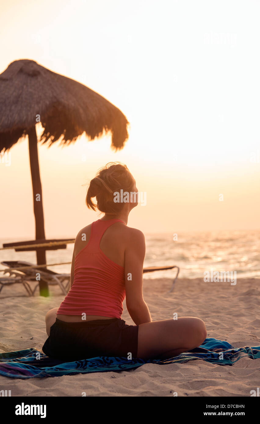 Messico, Playa del Carmen, giovane donna a praticare yoga sulla spiaggia al sorgere del sole Foto Stock