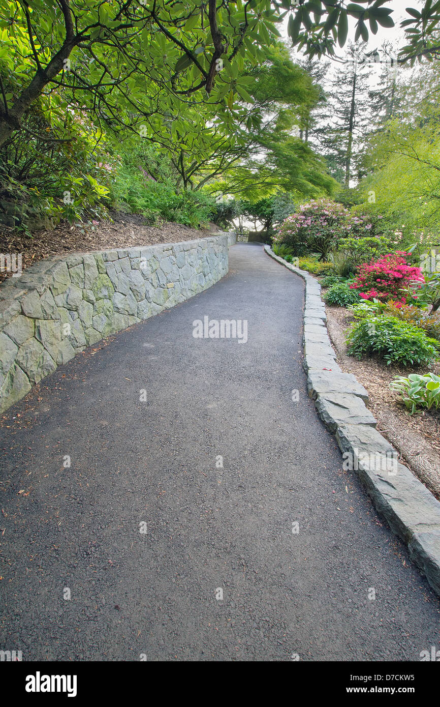 A piedi il percorso di asfalto con la pietra di parete di ritegno a Crystal Springs Rhododendron Garden Foto Stock