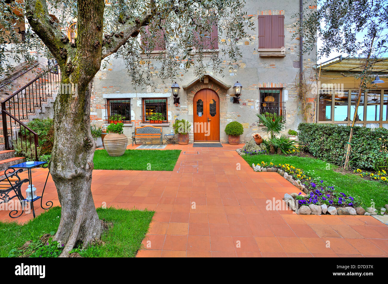 Bella terrazza con alberi e fiori all'ingresso ristorante situato in tipica casa italiana a Sirmione, Italia. Foto Stock