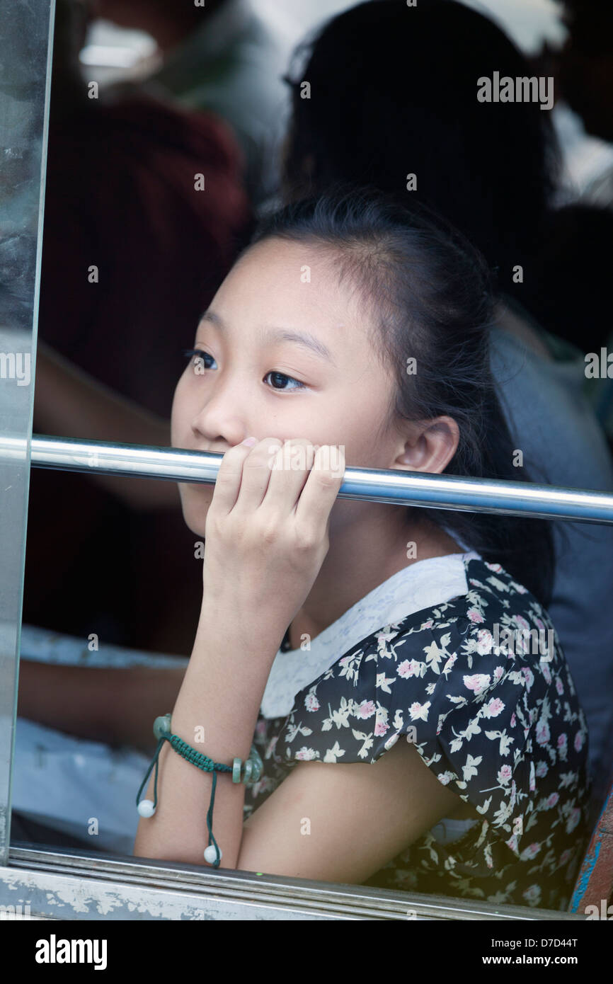 Una bella giovane ragazza birmano sguardi fuori da una finestra di bus a Yangon, Myanmar Foto Stock