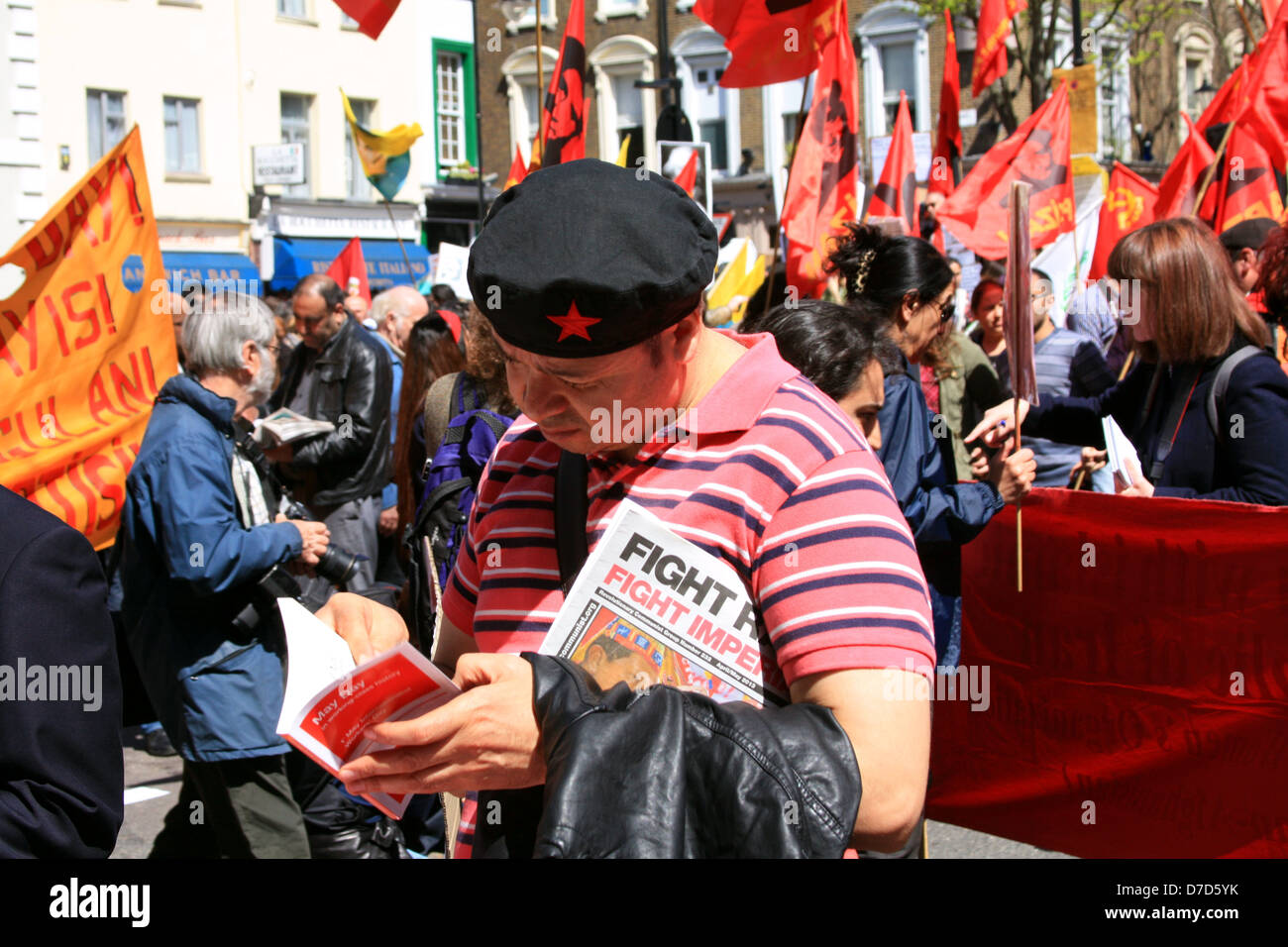 Giorno di maggio sfilano a Londra, 2013. Un partecipante legge letteratura sull'evento in una fase di stallo sul verde. Foto Stock