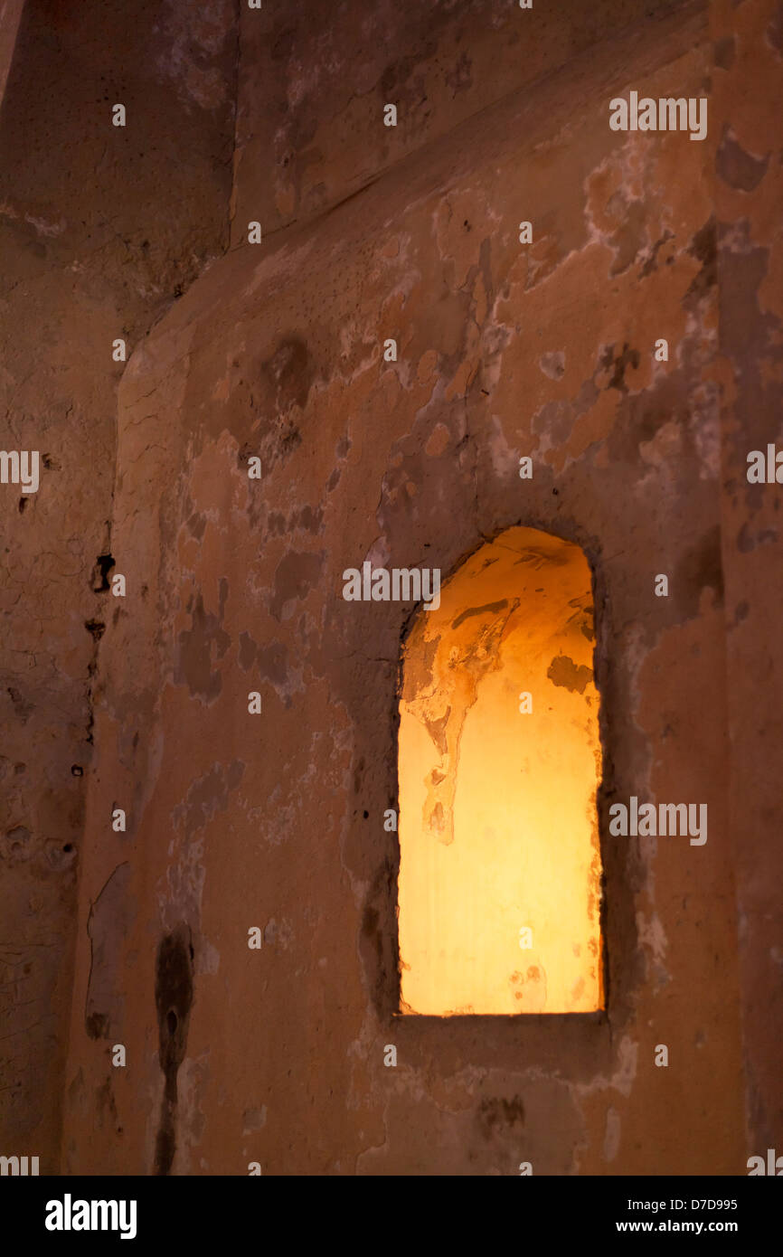 Finestra ad arco come parte di un antico edificio, arancione luce al tungsteno provenienti dall'interno. Foto Stock