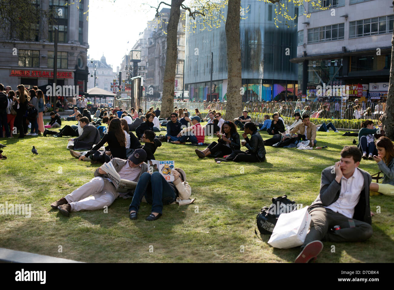 Leicester Square, Londra Inghilterra persone rilassante sull'erba Foto Stock