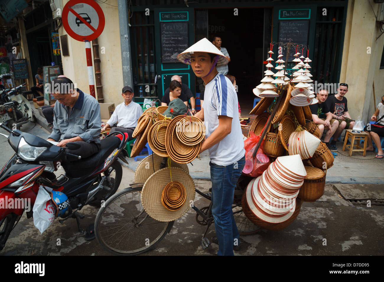 Un uomo vendere il riso cappelli e cesti dalla sua bicicletta nel vecchio quartiere, Hanoi. Foto Stock